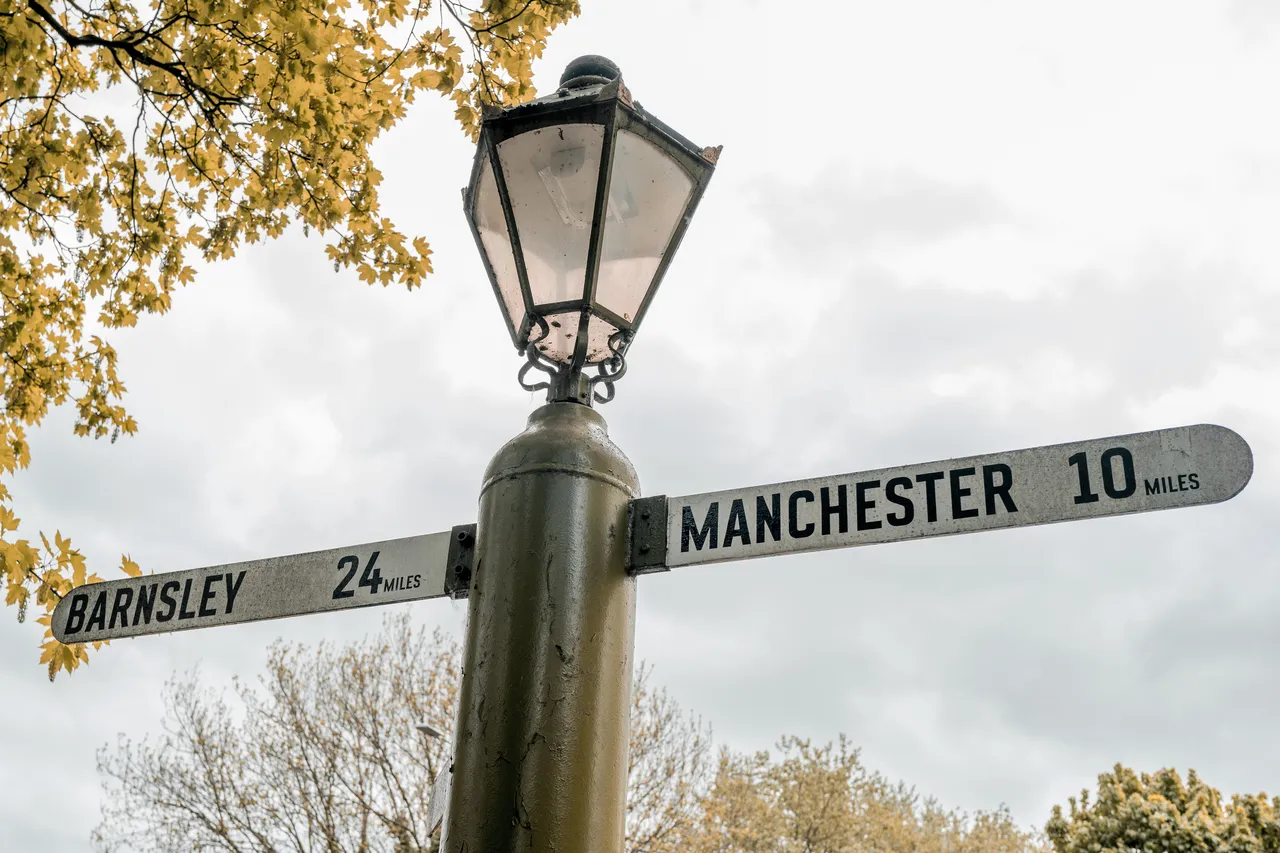 A traditional road sign with distances. One way points to Manchester, the other to Barnsley.